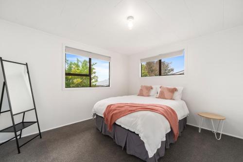 a white bedroom with a bed and two windows at Garden Grove Gem - Lake Taupō Holiday Home in Taupo