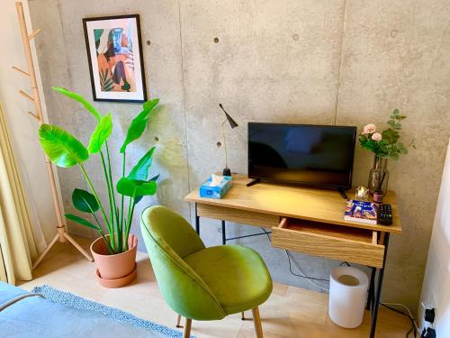 a desk with a computer and a green chair in a room at Ken's Place四谷 in Tokyo