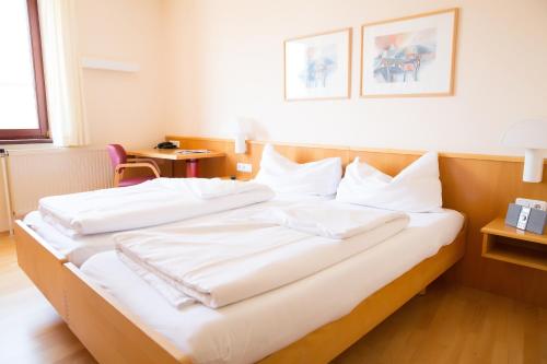 a bedroom with a large bed with white sheets at Das Reinisch Just Rooms in Schwechat