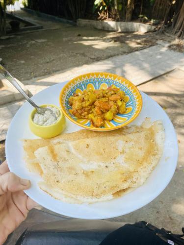 a plate of food on a table with a plate of food at Petit Ana Beach Retreat in Varkala