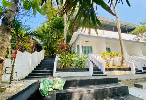 a white house with stairs in front of it at Petit Ana Beach Retreat in Varkala
