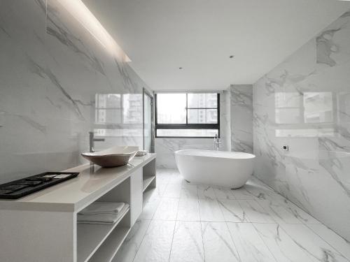 a white bathroom with a tub and a sink at CHECK inn Taichung Qinghai in Taichung