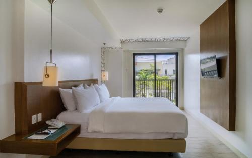 a hotel room with a bed and a balcony at Quest Hotel Tagaytay in Tagaytay