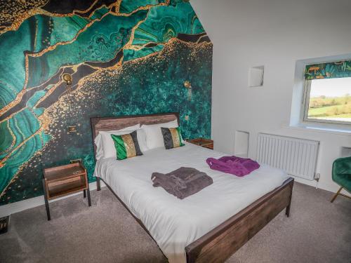 a bedroom with a bed with a painting on the wall at Pastures Barn in Leek