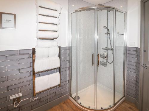 a shower in a bathroom with white towels at Parlour Barn in Leek