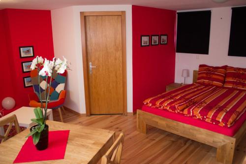 Dormitorio rojo con cama y mesa en B&B Les Biolleys, en Vex
