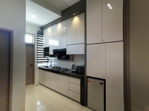 uma cozinha com armários brancos e um frigorífico em S H Homestay Bagan Lalang em Sungai Pelik