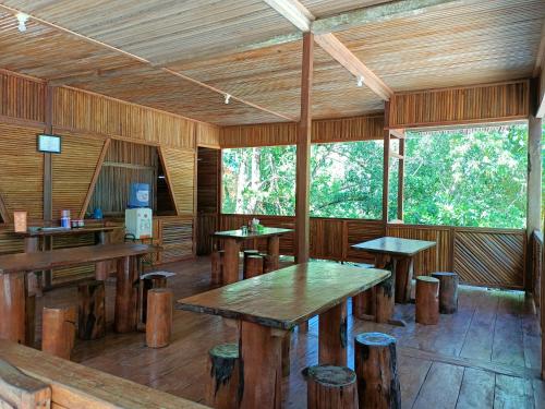 pokój z drewnianymi stołami i stołkami w kabinie w obiekcie Sing Key Beach w mieście Masohi