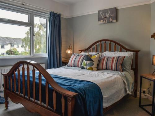 um quarto com uma cama com almofadas e uma janela em The Warblers em Minehead