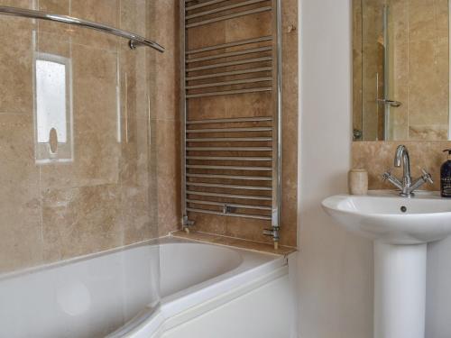 a bathroom with a sink and a bath tub and a toilet at The Warblers in Minehead