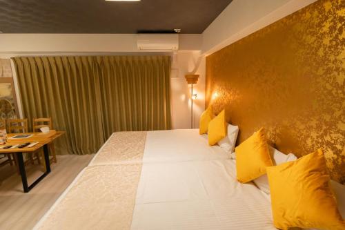 a hotel room with a large bed with yellow pillows at Japan Hinata Hotel 池下駅 1番出口 徒歩2分 1LDK 50平米 8名 in Nagoya
