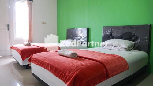 two beds in a room with green walls at El Dhiya Syariah Karawaci RedPartner in Tangerang