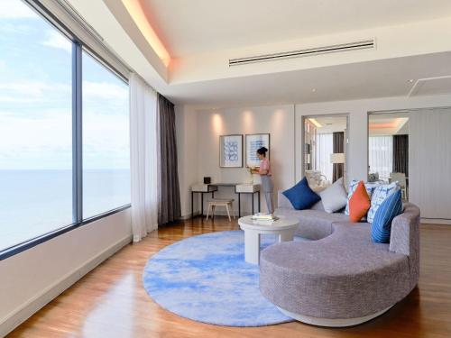 a living room with a couch and a large window at Amari Pattaya in Pattaya Central