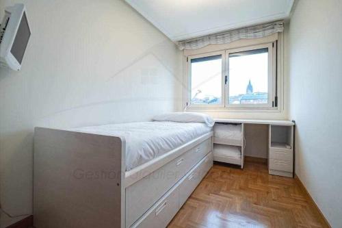 Habitación pequeña con cama y ventana en Santo domingo Apartamento, en Oviedo