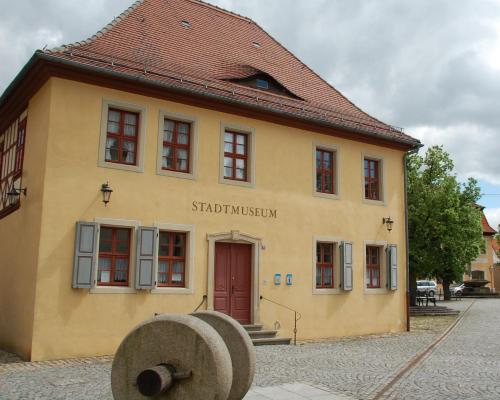 a small yellow building with a red door at Hotel & Café Mohrenbrunnen in Eisenberg