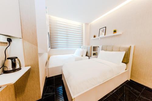 two beds in a small room with a window at D'Nova Hotel Bugis in Singapore