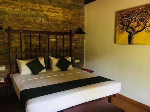 a bedroom with a bed with a tree painting on the wall at The Coastal Village Cabanas in Galle