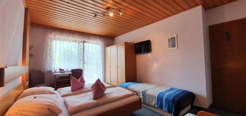 1 dormitorio con 2 camas y ventana en Pension Mühlenheim, en Egg am Faaker See