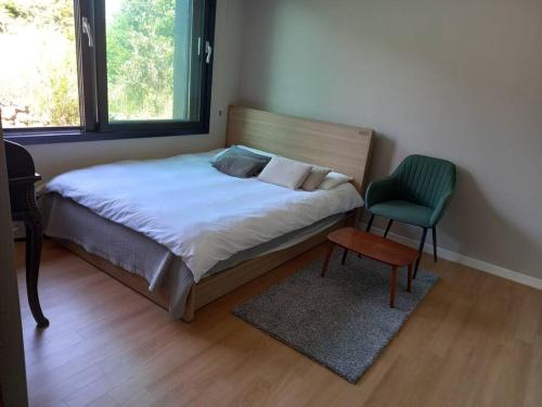 um quarto com uma cama, uma cadeira e uma janela em Sogobe Jeju House em Jeju