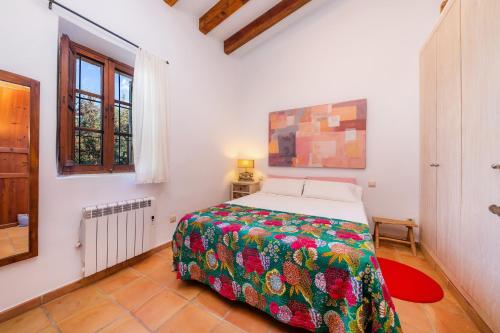 sypialnia z łóżkiem z kolorowym kocem w obiekcie Finca Na Palada w mieście Artá