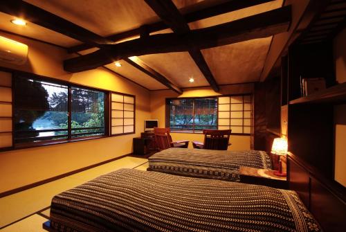 two beds in a room with two windows at Taikyourou in Miyazu