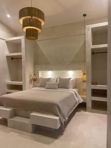 a bedroom with a large bed and a chandelier at CASA NARA BALI in Munggu