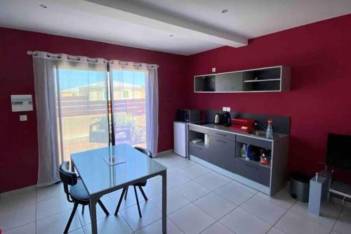 a kitchen with a table and a red wall at Enonatja Studio - 5min des plages et du centre de St Pierre in Saint-Pierre