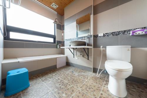 a bathroom with a toilet and a sink and a window at Rococo Homestay in Hengchun