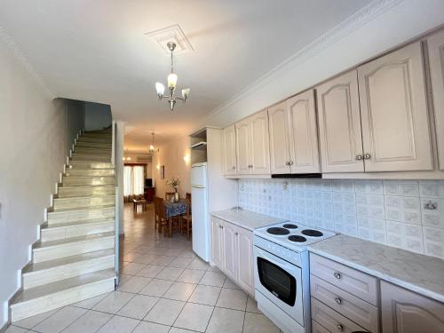 a kitchen with white cabinets and a stove and a staircase at Ethereal Villas Lefkas in Nydri