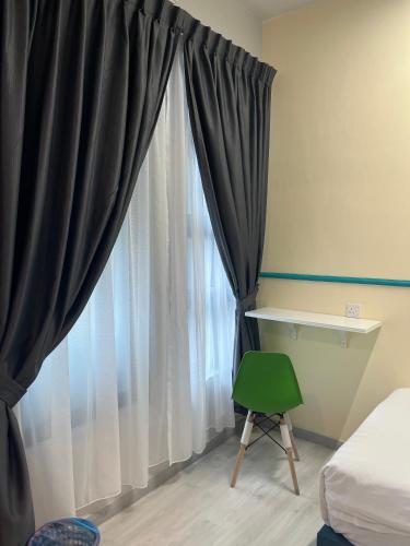 a bedroom with black curtains and a green chair at Splendours Condos@Jesselton Quay in Kota Kinabalu