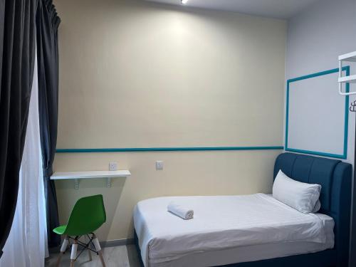 a small bedroom with a bed and a green chair at Splendours Condos@Jesselton Quay in Kota Kinabalu