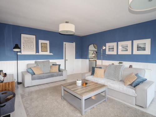 a living room with two couches and a table at Nyth Y Fran in Abersoch