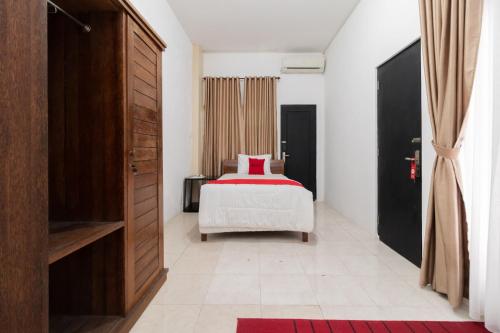 a bedroom with a bed with a red blanket at RedDoorz Syariah at Jalan Andalas Padang in Kampungdurian