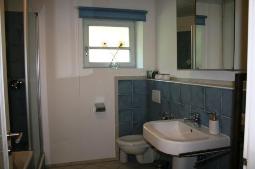 łazienka z umywalką, toaletą i oknem w obiekcie Ferienwohnung am Herrnberg w mieście Prien am Chiemsee