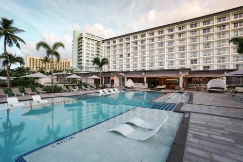 a hotel swimming pool with white chairs and a hotel at Crowne Plaza Resort Guam in Tumon