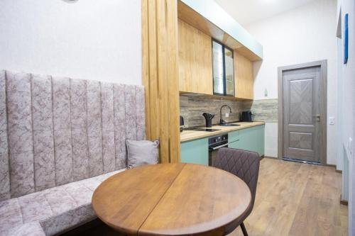 a kitchen with a wooden table and a couch at Nino's Cosy Apartment in Kutaisi