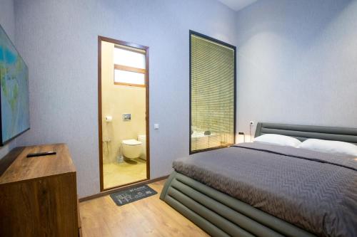 a bedroom with a bed and a bathroom with a window at Nino's Cosy Apartment in Kutaisi
