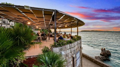 a restaurant with people sitting on a pier next to the water at Hotel Splendid in Dubrovnik