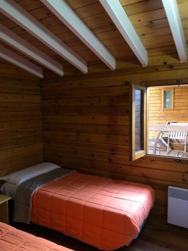 a log cabin with a bed in a room with a window at Camping Cambrils Caban in Cambrils