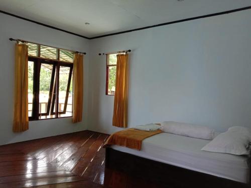 Masohi的住宿－Sing Key Beach，一间卧室设有一张床和两个窗户。