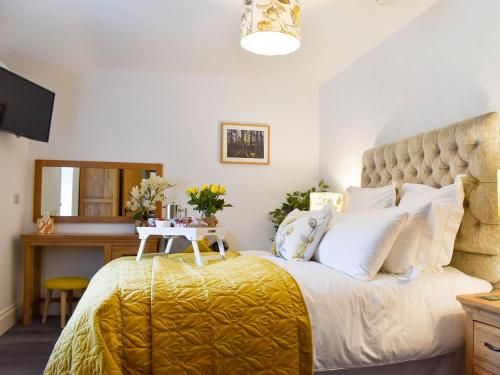 a bedroom with a large bed with a yellow blanket at Thistle Cottage - Uk30523 in Staintondale
