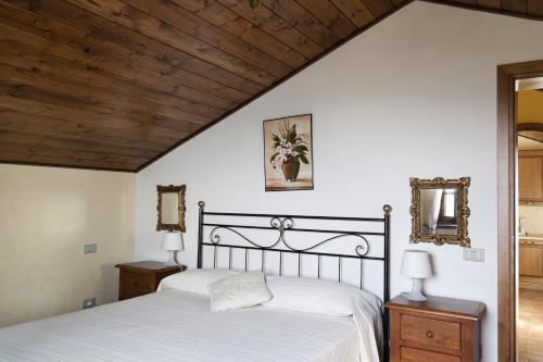 Un dormitorio con una cama con sábanas blancas y techos de madera. en Montefiore Casa Vacanze, en Lamporecchio