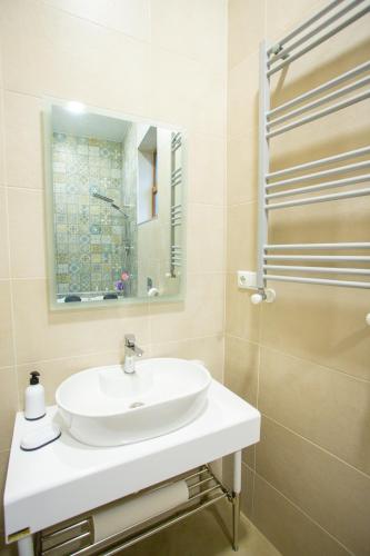 a white bathroom with a sink and a mirror at Nino's Cosy Apartment in Kutaisi