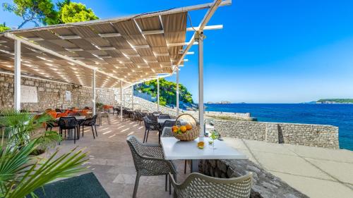 een patio met een tafel en stoelen en de oceaan bij Hotel Splendid in Dubrovnik