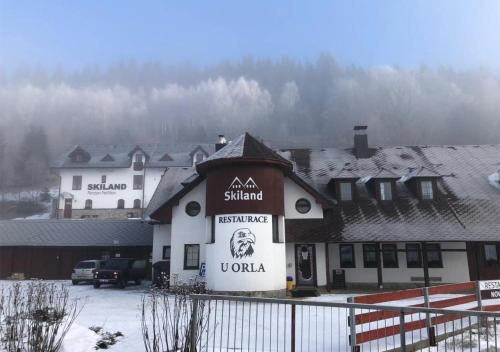 a building with a sign on it in the snow at Penzion U Orla in Petříkov