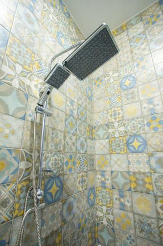 a shower with a shower head on a tiled wall at Nino's Cosy Apartment in Kutaisi