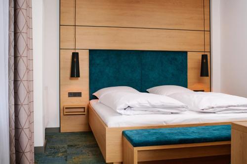 a bedroom with a large bed with a blue headboard at Hotel SCHNEIDER in Allersberg