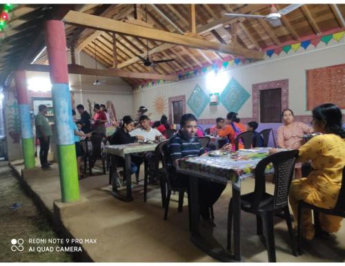 Rann Chandni Resort, Kutch, Bhuj في Bherandiāla: مجموعة من الناس يجلسون على الطاولات في الغرفة