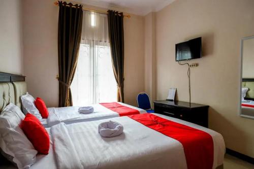 una camera d'albergo con un grande letto con cuscini rossi di RedDoorz at Makale Tana Toraja a Makale