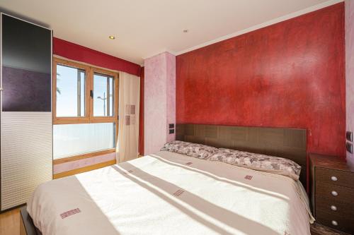 a bedroom with a large bed and a red wall at Apto Villajoyosa 1ª línea in Villajoyosa